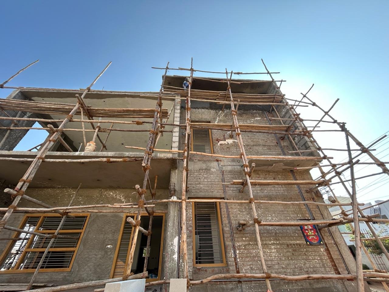 Low angle view of a building structure with scaffolding, worker at top